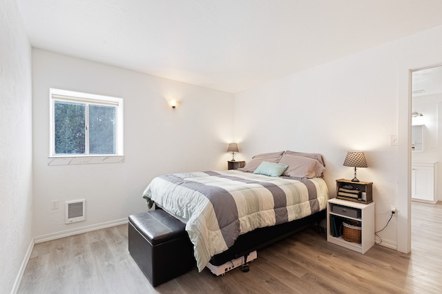 bedroom featuring light hardwood / wood-style flooring and ensuite bath