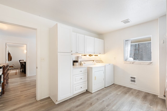 laundry area with cabinets, washer and clothes dryer, heating unit, and light hardwood / wood-style floors