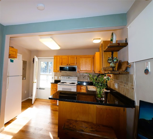 kitchen with kitchen peninsula, backsplash, white appliances, and light hardwood / wood-style floors