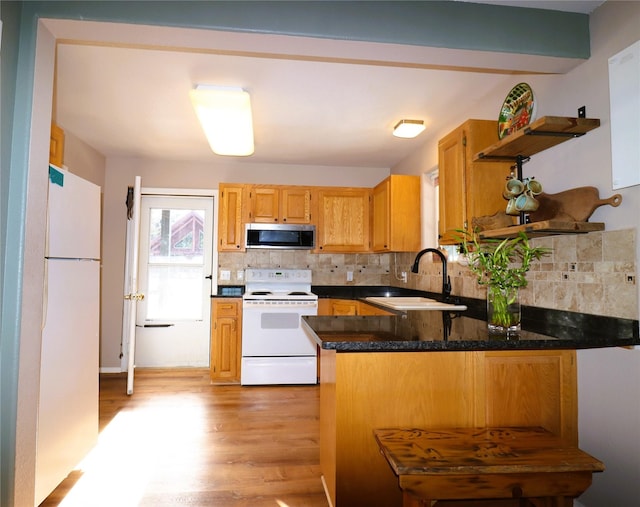 kitchen with white appliances, sink, light hardwood / wood-style flooring, kitchen peninsula, and backsplash