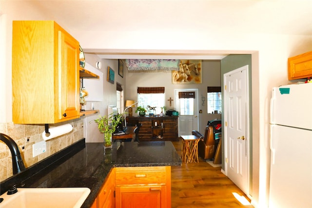 kitchen featuring kitchen peninsula, dark hardwood / wood-style flooring, sink, decorative backsplash, and white fridge