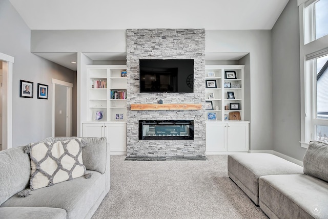 carpeted living room with a wealth of natural light, built in features, and a stone fireplace