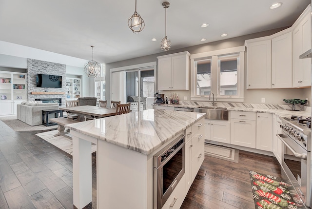 kitchen featuring a center island, sink, light stone countertops, high end stainless steel range, and white cabinets