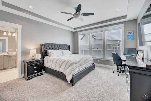 bedroom featuring ensuite bathroom, ceiling fan, a raised ceiling, carpet flooring, and multiple windows