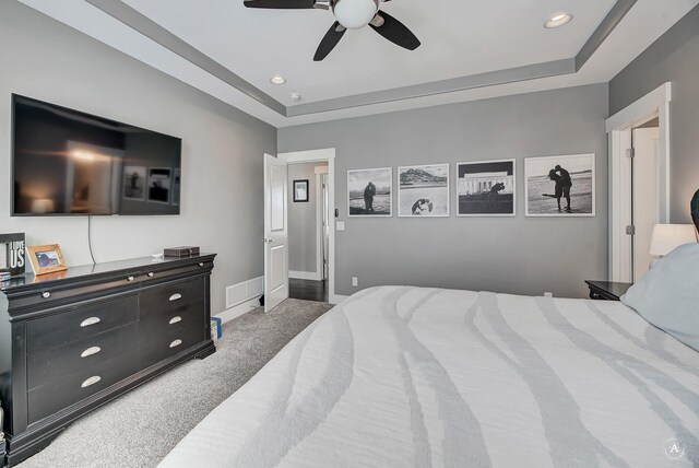 bedroom featuring ceiling fan, a raised ceiling, and dark colored carpet