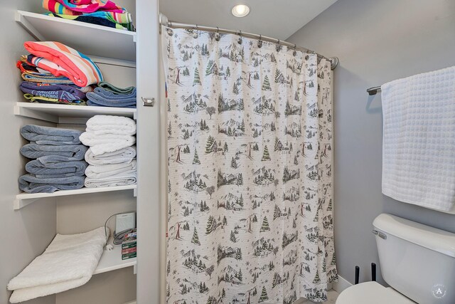 bathroom featuring toilet and curtained shower