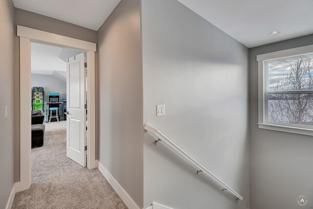 hall featuring light colored carpet and lofted ceiling