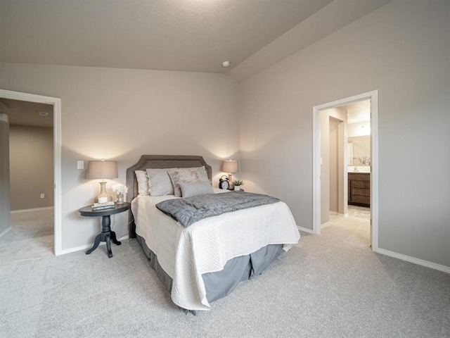 carpeted bedroom with vaulted ceiling and connected bathroom