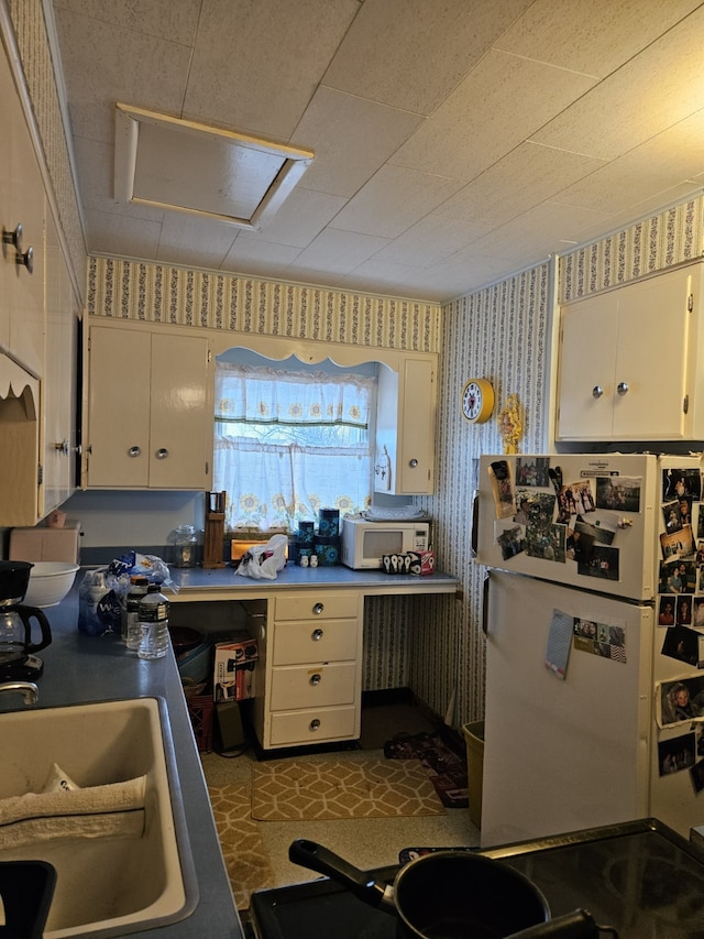 kitchen with white cabinetry, sink, and white appliances