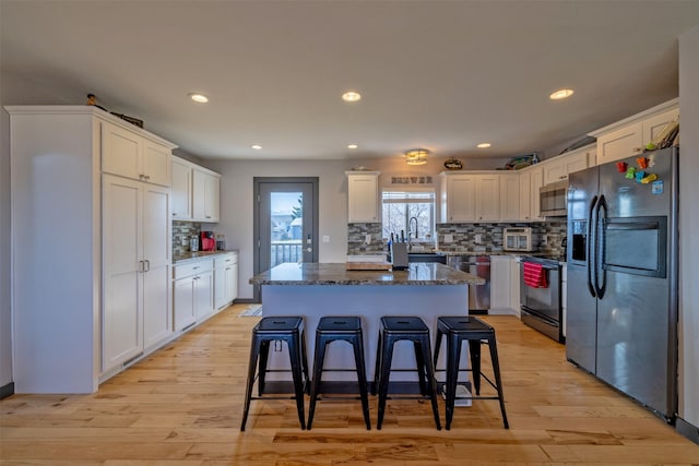 3761 Aster St, East Helena, MT 59635 - kitchen with dark stone counters, white cabinetry, a kitchen island, stainless steel appliances, and decorative backsplash