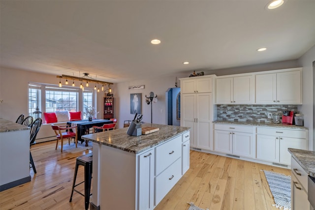 3761 Aster St, East Helena, MT 59635 - kitchen featuring light wood-style flooring, backsplash, white cabinetry, and a kitchen island