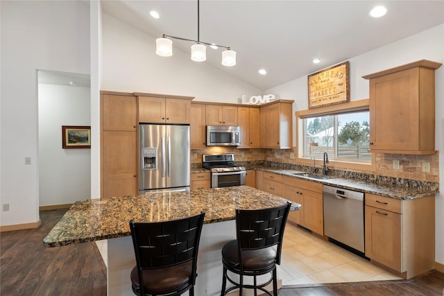 115 Stryker Peak Trl, Kalispell, MT 59901 - kitchen featuring appliances with stainless steel finishes, a sink, tasteful backsplash, a breakfast bar area, and dark stone countertops