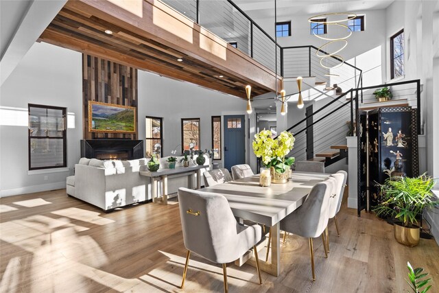 living room featuring beam ceiling, light hardwood / wood-style floors, and a towering ceiling