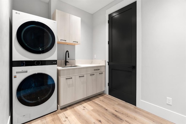 washroom with cabinets, sink, light hardwood / wood-style flooring, and stacked washer and clothes dryer