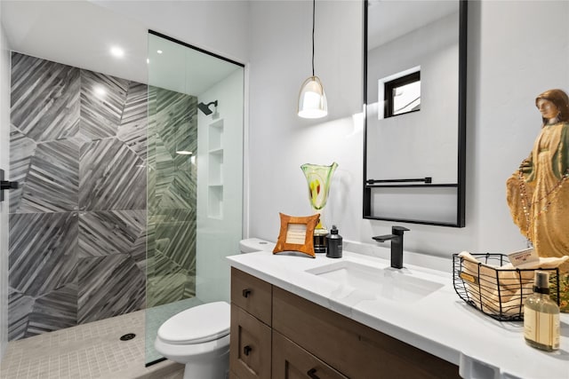 bathroom featuring tiled shower, vanity, and toilet