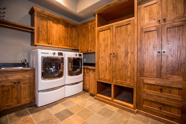 washroom with cabinets, washing machine and clothes dryer, and sink