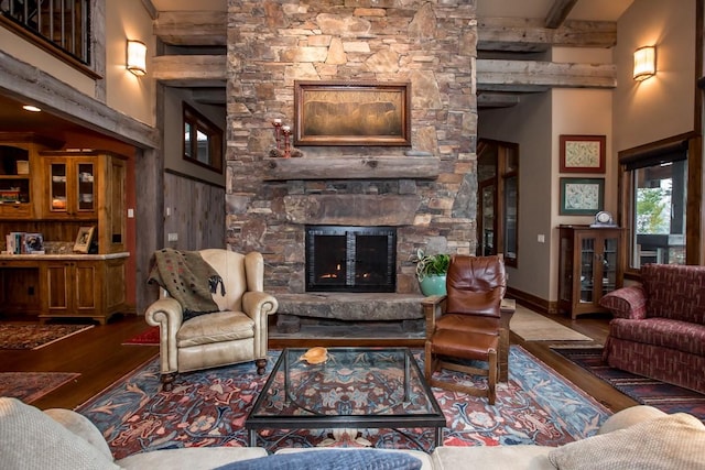 living room featuring a towering ceiling, wooden walls, a fireplace, beamed ceiling, and wood-type flooring