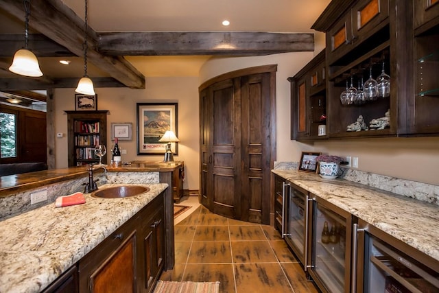 bar with decorative light fixtures, sink, beverage cooler, dark brown cabinets, and beam ceiling