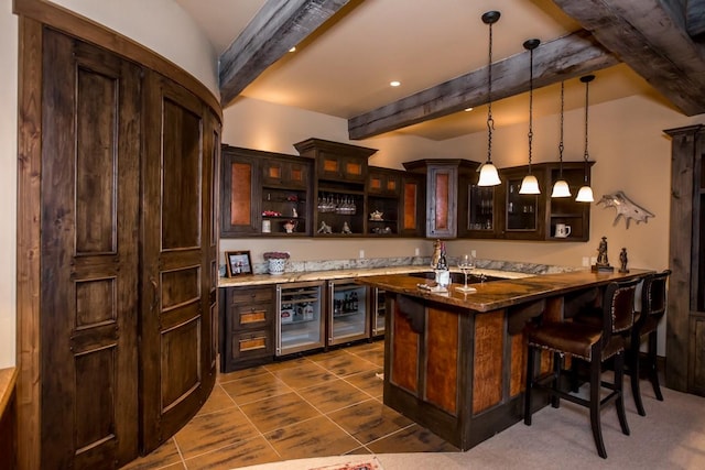 bar with beamed ceiling, dark brown cabinetry, beverage cooler, and hanging light fixtures