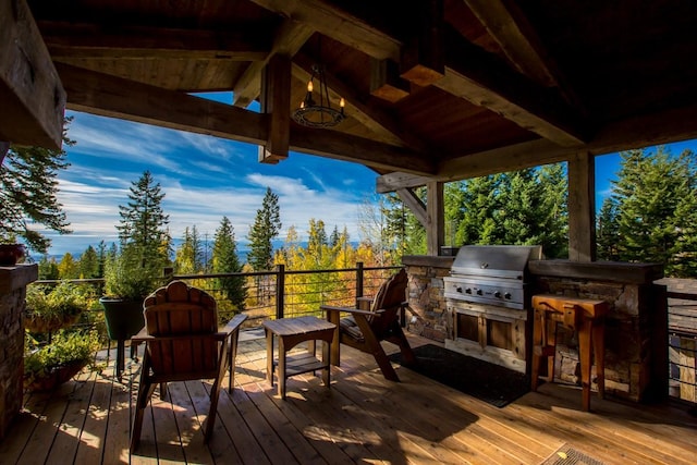 wooden deck with an outdoor kitchen, a grill, and exterior bar