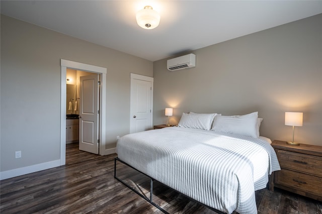 bedroom with an AC wall unit, ensuite bathroom, and dark hardwood / wood-style floors