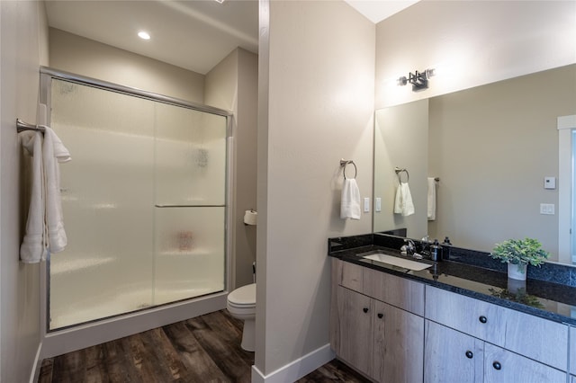 bathroom with hardwood / wood-style flooring, toilet, an enclosed shower, and vanity