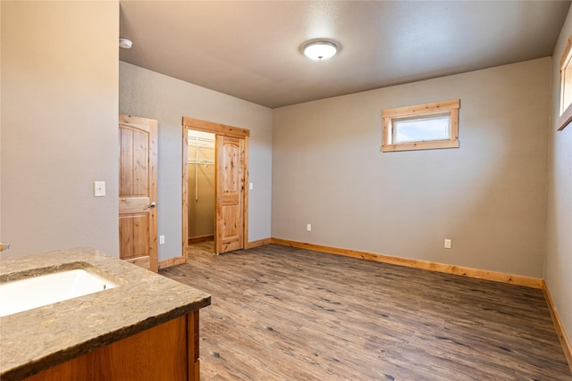 interior space with a walk in closet, baseboards, light wood-type flooring, and a sink