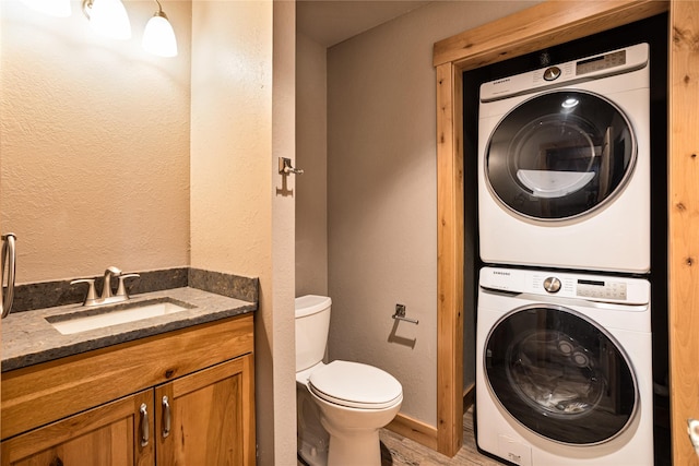 washroom featuring a sink, light wood finished floors, stacked washing maching and dryer, laundry area, and a textured wall