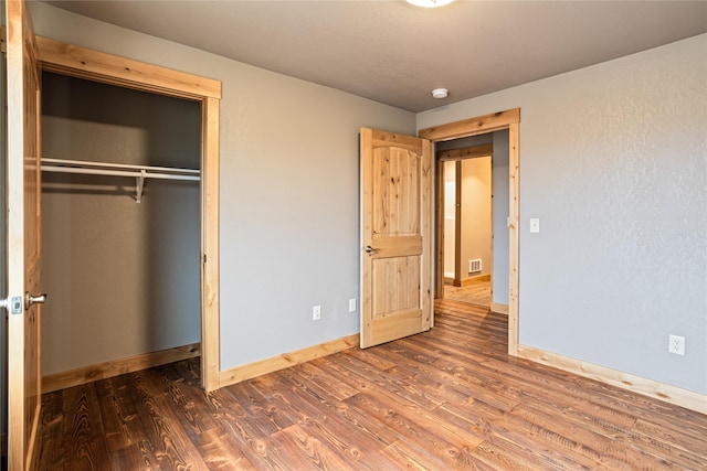 unfurnished bedroom with a closet and dark hardwood / wood-style flooring