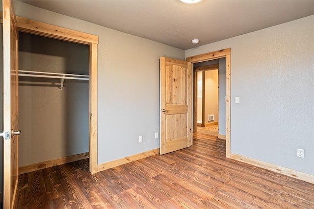 unfurnished bedroom with visible vents, baseboards, a closet, and wood finished floors