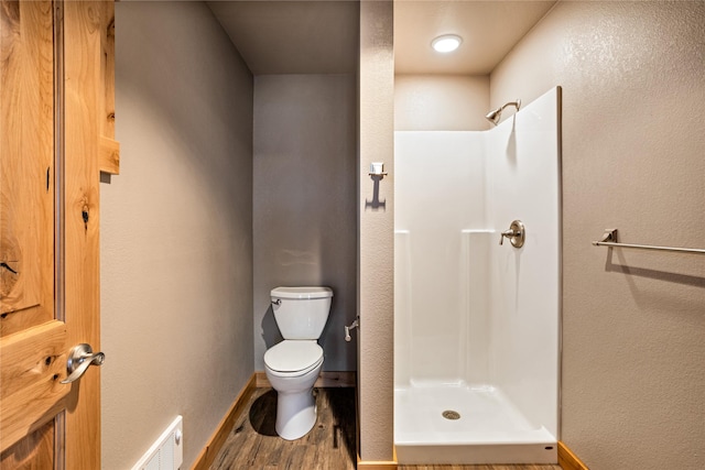 bathroom with toilet, visible vents, a stall shower, and wood finished floors