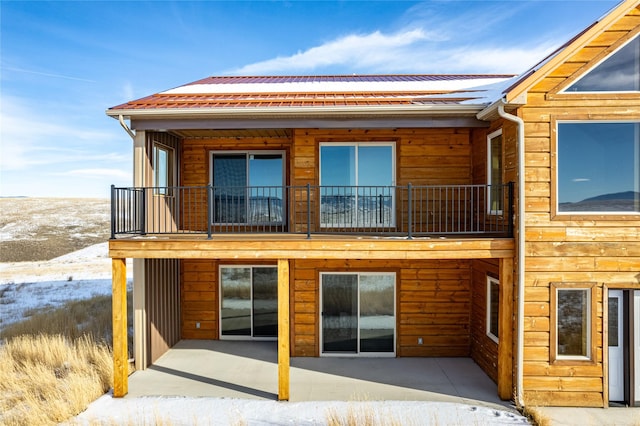 snow covered rear of property with a balcony and a patio area