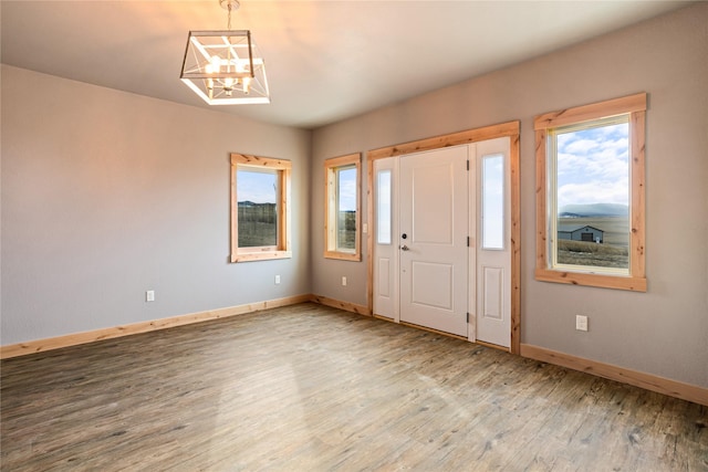 foyer entrance featuring baseboards, wood finished floors, and a chandelier