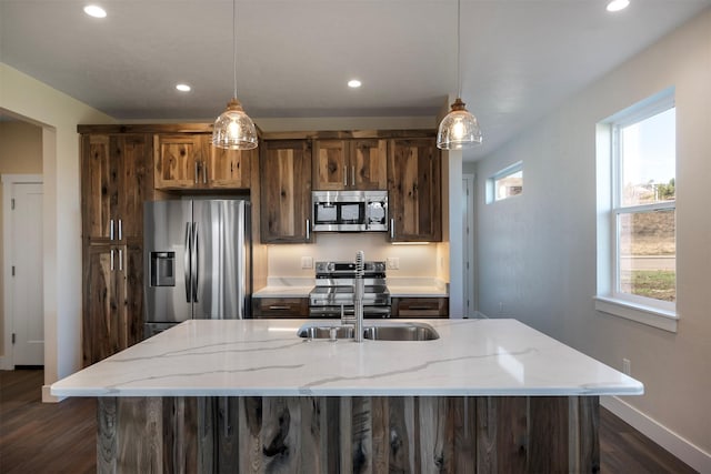 kitchen with hanging light fixtures, dark hardwood / wood-style floors, light stone counters, and stainless steel appliances