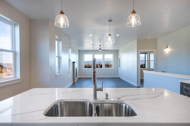 kitchen with light stone countertops, hanging light fixtures, and sink