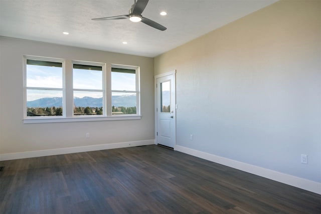 spare room featuring ceiling fan, dark hardwood / wood-style flooring, and a mountain view