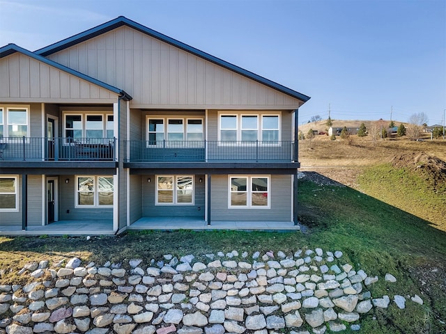 rear view of house featuring a balcony, a yard, and a patio