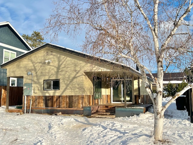 snow covered house featuring fence