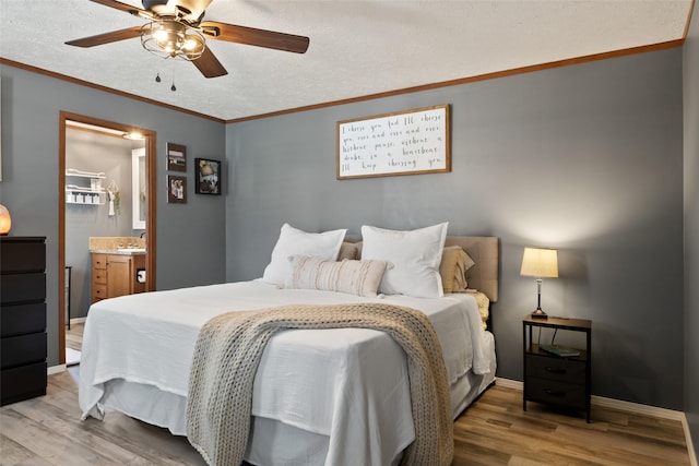 bedroom with a textured ceiling, ceiling fan, light hardwood / wood-style floors, and connected bathroom