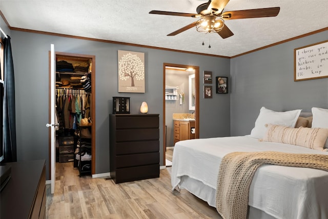 bedroom featuring ceiling fan, ensuite bath, a spacious closet, a textured ceiling, and a closet