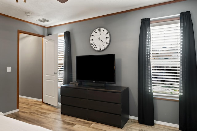 bedroom featuring light wood-type flooring, multiple windows, and ornamental molding