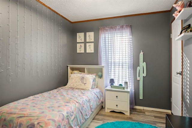 bedroom with light hardwood / wood-style floors, a textured ceiling, and crown molding