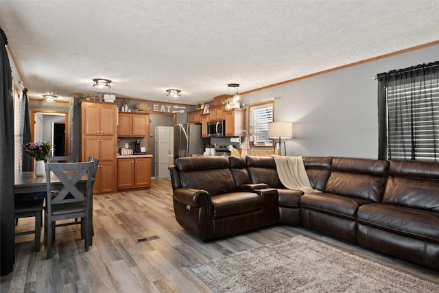 living room featuring a textured ceiling, ornamental molding, and light hardwood / wood-style floors