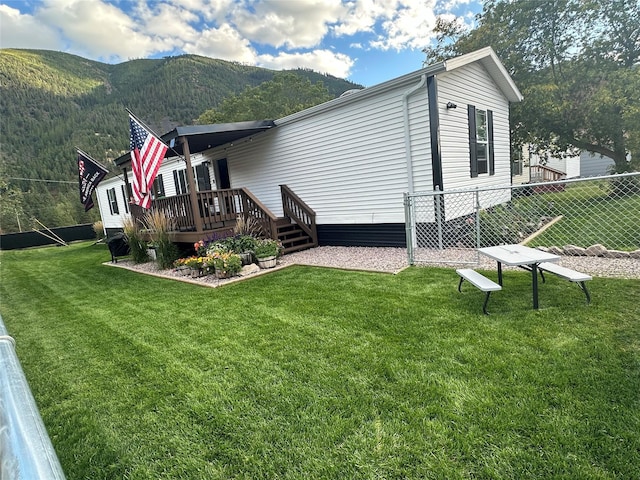 view of side of home featuring a yard and a deck with mountain view