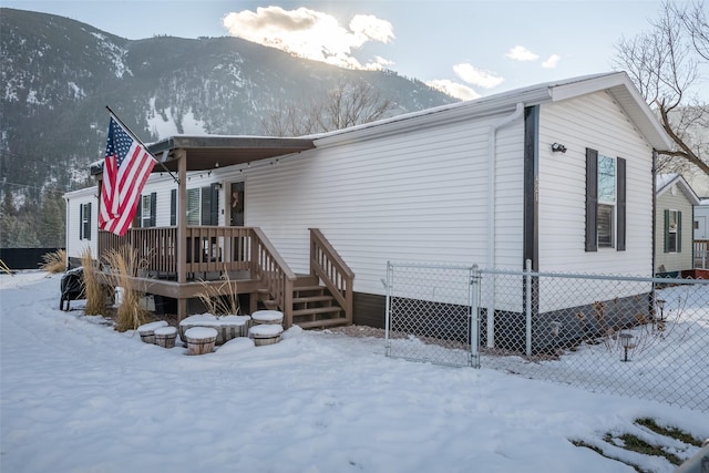 snow covered house featuring a deck with mountain view