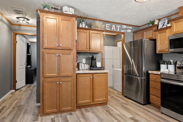 kitchen featuring light hardwood / wood-style floors, a textured ceiling, appliances with stainless steel finishes, and ornamental molding