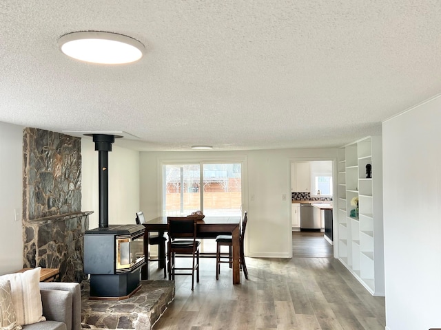 dining room featuring a textured ceiling, a wood stove, and wood finished floors