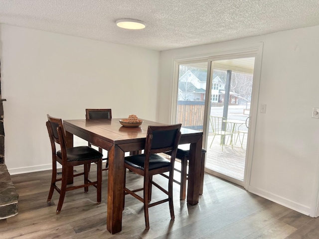 dining space with wood finished floors, baseboards, and a textured ceiling