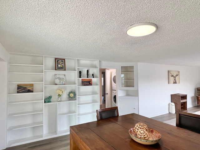 dining area featuring wood finished floors, stacked washer and clothes dryer, and a textured ceiling