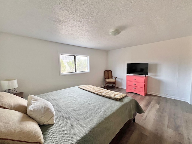 bedroom featuring wood finished floors, baseboards, and a textured ceiling